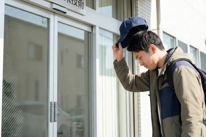 建物に入る前に帽子を脱ぐ実習生